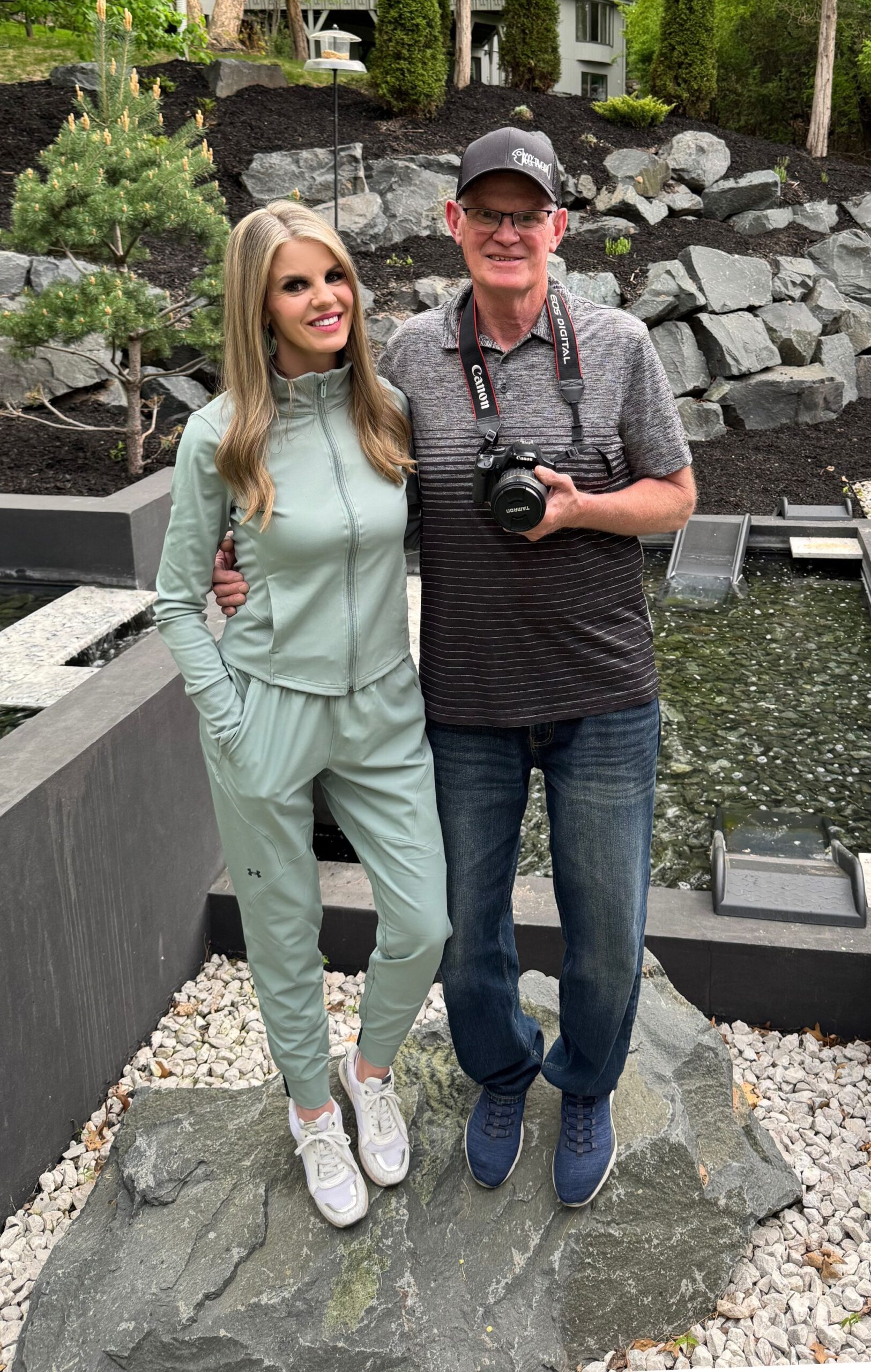 Woman and man standing on a rock in front of pond, man with a camera in his hands